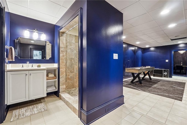 bathroom with tile patterned flooring, vanity, and tiled shower