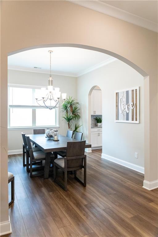 2665 Crowbrook Way, Cumming, GA 30040 - dining area featuring dark wood finished floors, arched walkways, a chandelier, baseboards, and crown molding