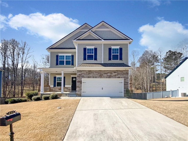 craftsman-style house with fence, a porch, a garage, stone siding, and driveway
