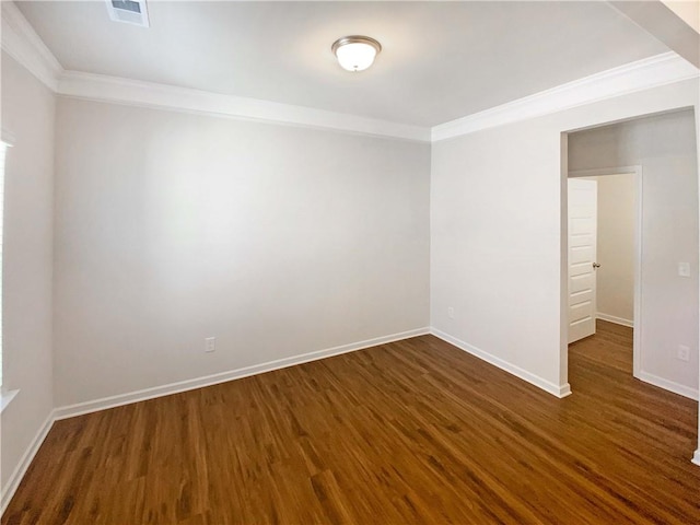 empty room featuring visible vents, dark wood-type flooring, baseboards, and ornamental molding