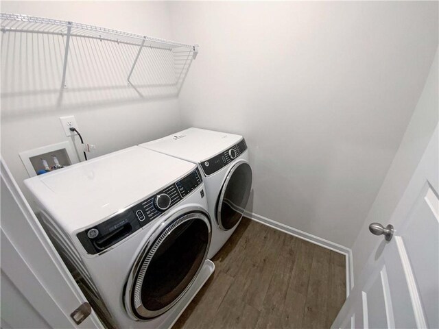 laundry room with laundry area, washer and dryer, dark wood-type flooring, and baseboards