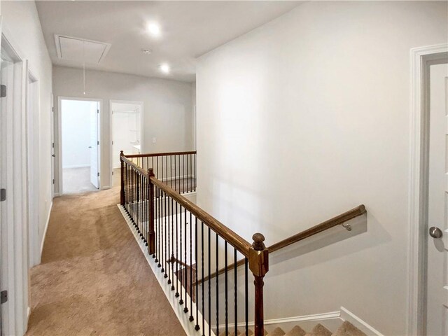 hall featuring an upstairs landing, attic access, and light carpet