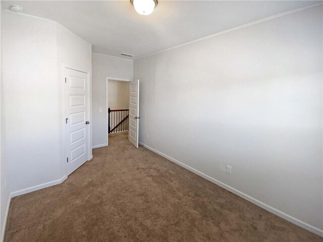 empty room with carpet flooring, visible vents, and baseboards