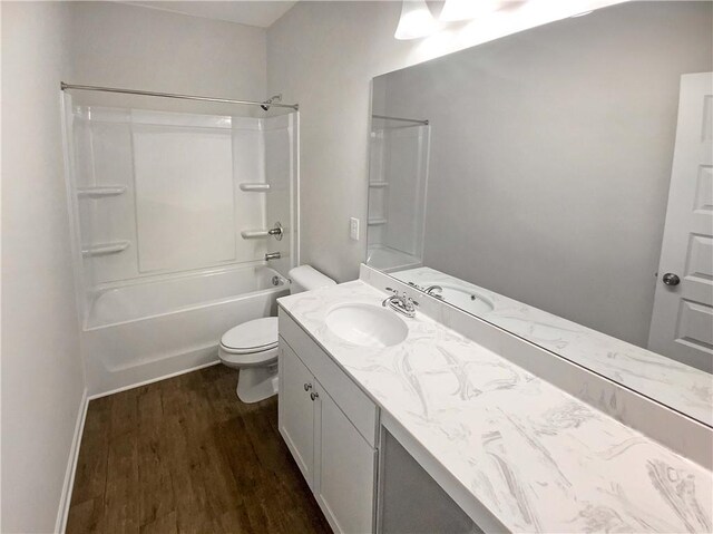 bathroom featuring baseboards, toilet, wood finished floors, vanity, and  shower combination
