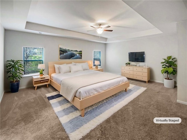 bedroom featuring ceiling fan, baseboards, a raised ceiling, and carpet