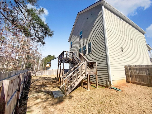 rear view of house featuring stairway and a fenced backyard