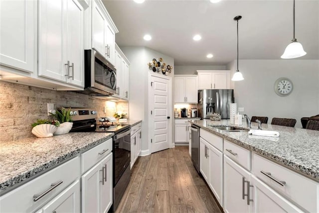 1311 Calgary Lk, Winder, GA 30680 - kitchen with stainless steel appliances, wood finished floors, white cabinetry, hanging light fixtures, and decorative backsplash
