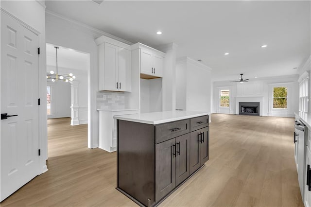 kitchen with backsplash, crown molding, ceiling fan with notable chandelier, and white cabinets