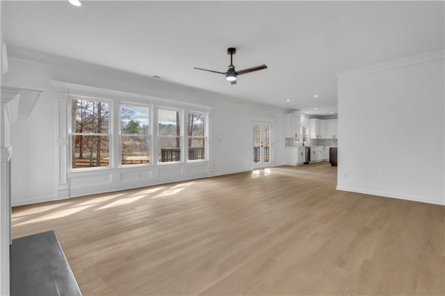 unfurnished living room featuring crown molding, ceiling fan, light hardwood / wood-style flooring, and a wealth of natural light