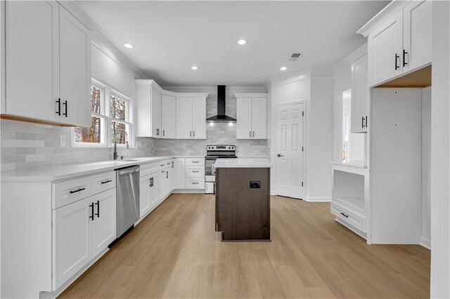 kitchen with a kitchen island, white cabinetry, appliances with stainless steel finishes, and wall chimney range hood