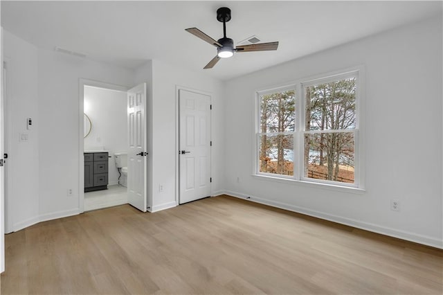 unfurnished bedroom featuring multiple windows, ensuite bath, light hardwood / wood-style flooring, and ceiling fan