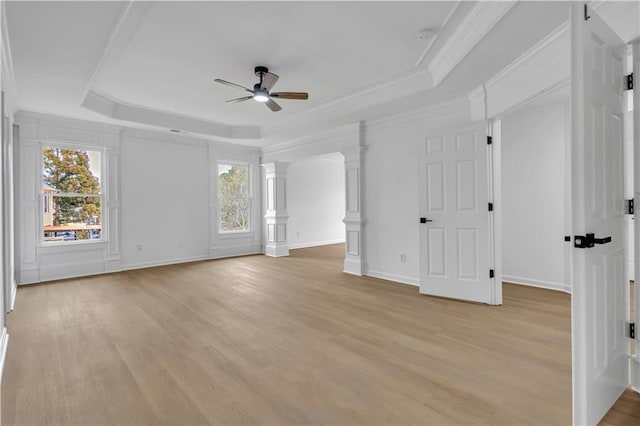 empty room featuring a tray ceiling, a wealth of natural light, and decorative columns