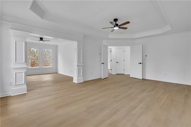 unfurnished living room featuring a raised ceiling, crown molding, light wood-type flooring, and decorative columns