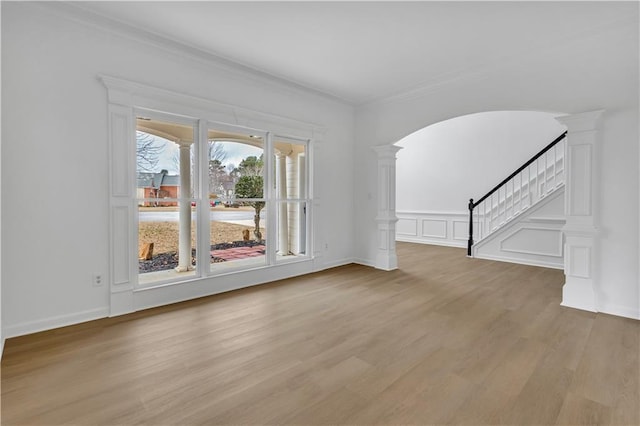 unfurnished living room featuring light hardwood / wood-style flooring, ornamental molding, and ornate columns