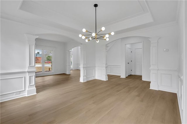 unfurnished dining area with hardwood / wood-style flooring, decorative columns, and a raised ceiling