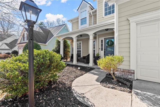 view of exterior entry featuring covered porch and a garage