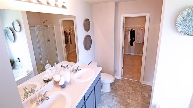 bathroom featuring a shower with door, vanity, and toilet