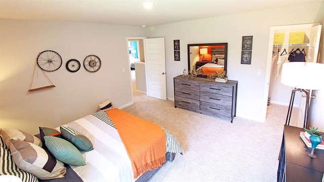 bedroom with a spacious closet, a closet, and light carpet