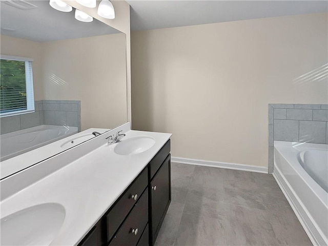 bathroom with double vanity, a garden tub, baseboards, and a sink