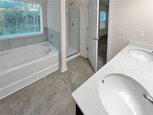 full bath with a sink, a shower stall, double vanity, and a garden tub