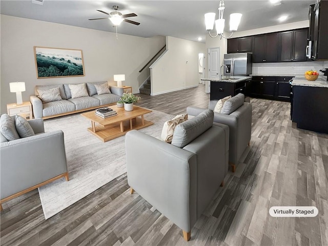 living area featuring stairs, a ceiling fan, and wood finished floors
