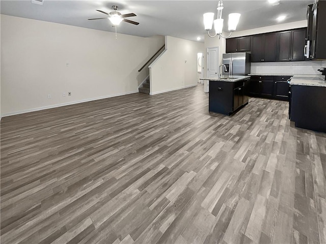 kitchen with open floor plan, an island with sink, light countertops, decorative light fixtures, and wood finished floors