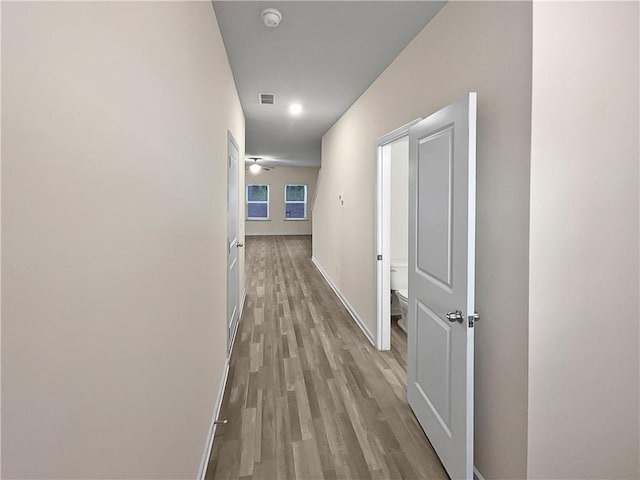 hall with wood finished floors, baseboards, and visible vents