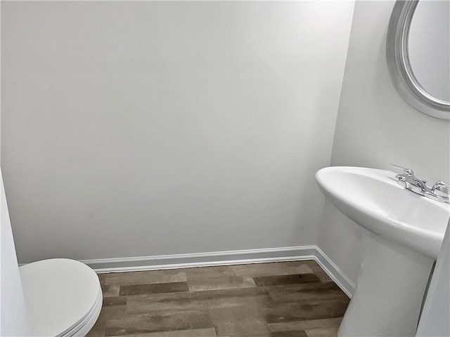 bathroom with toilet, wood finished floors, and baseboards