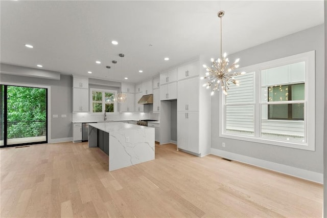 1420 Coretta Bnd, Atlanta, GA 30318 - kitchen featuring under cabinet range hood, light wood-style flooring, light stone countertops, a kitchen island, and baseboards