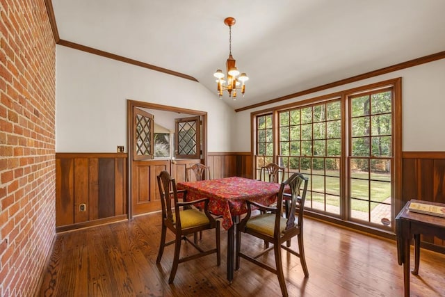 dining area featuring vaulted ceiling, a chandelier, ornamental molding, and hardwood / wood-style floors