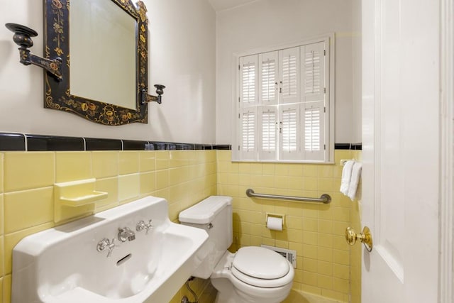 bathroom with sink, toilet, and tile walls