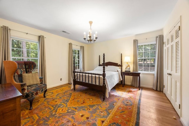 bedroom with hardwood / wood-style flooring, multiple windows, and a chandelier