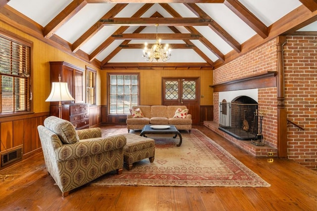 living room featuring dark wood-type flooring, beamed ceiling, high vaulted ceiling, a chandelier, and a brick fireplace