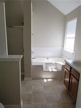 1752 Spring Hill Cv, Lithonia, GA 30058 - bathroom with vanity, a garden tub, and vaulted ceiling