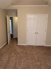 1752 Spring Hill Cv, Lithonia, GA 30058 - unfurnished bedroom with lofted ceiling, baseboards, a closet, and carpet flooring