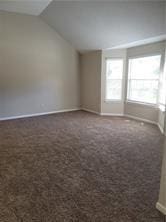 1752 Spring Hill Cv, Lithonia, GA 30058 - spare room featuring lofted ceiling, baseboards, and dark colored carpet