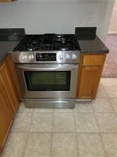 1752 Spring Hill Cv, Lithonia, GA 30058 - kitchen with stainless steel gas range, light tile patterned floors, and brown cabinets