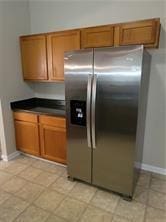 1752 Spring Hill Cv, Lithonia, GA 30058 - kitchen with stainless steel refrigerator with ice dispenser, brown cabinetry, baseboards, and dark countertops