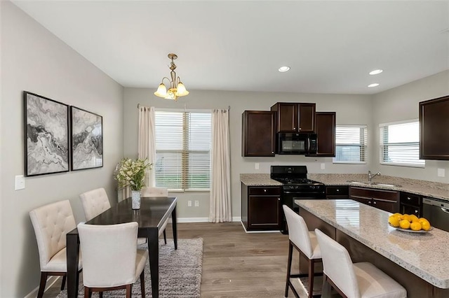 kitchen with a kitchen island, pendant lighting, sink, black appliances, and light stone countertops