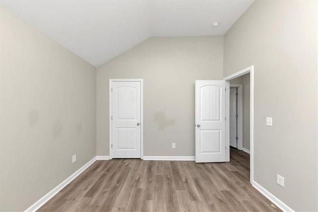 unfurnished bedroom with vaulted ceiling and light hardwood / wood-style floors