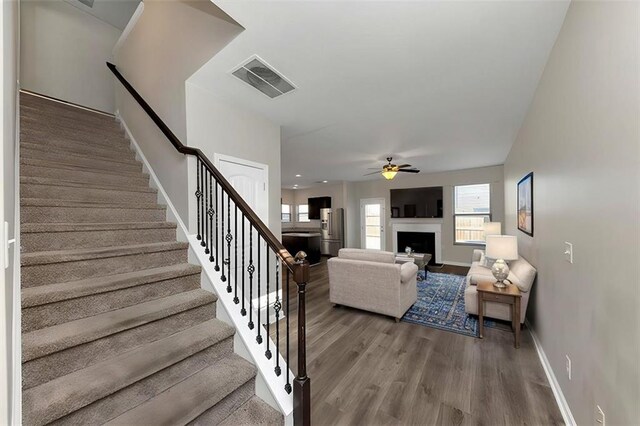 stairs with hardwood / wood-style floors and ceiling fan