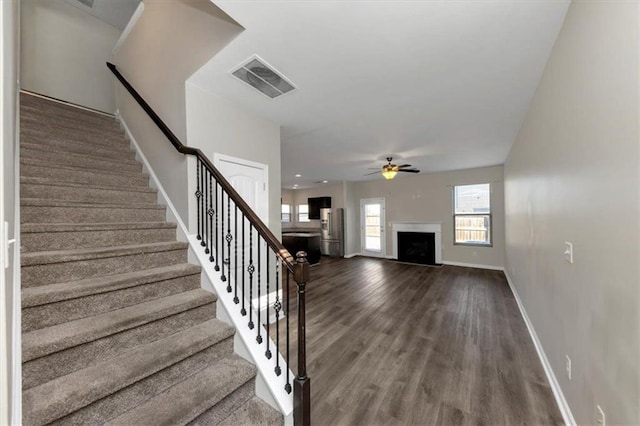 stairway with wood-type flooring and ceiling fan