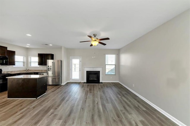 kitchen featuring high end fridge, dark brown cabinets, a kitchen island, ceiling fan, and hardwood / wood-style floors