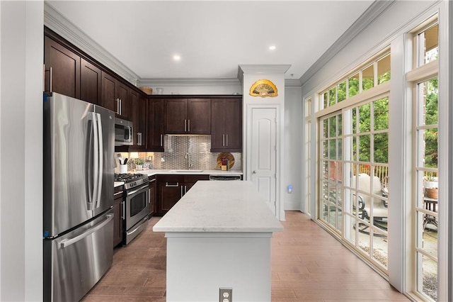 1055 Piedmont Ave NE Unit 106, Atlanta, GA 30309 - kitchen featuring stainless steel appliances, ornamental molding, a center island, dark brown cabinets, and decorative backsplash