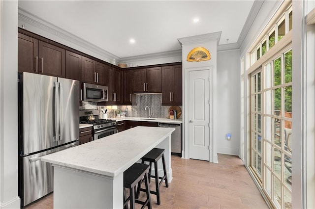 1055 Piedmont Ave NE Unit 106, Atlanta, GA 30309 - kitchen featuring appliances with stainless steel finishes, dark brown cabinetry, a kitchen bar, crown molding, and decorative backsplash