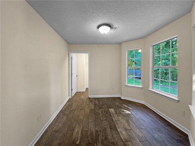 unfurnished room featuring dark wood-type flooring, a textured ceiling, and plenty of natural light