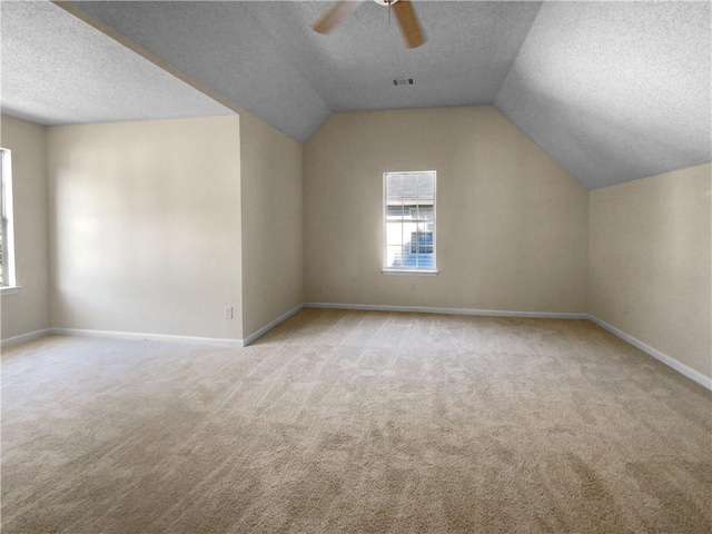 bonus room with ceiling fan, a textured ceiling, vaulted ceiling, and light colored carpet