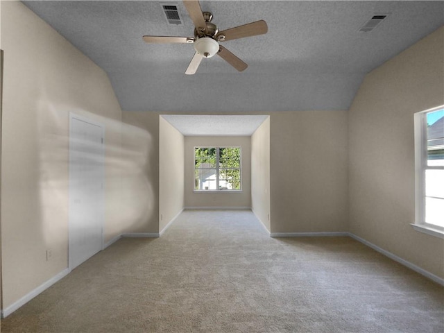 carpeted spare room featuring lofted ceiling, a textured ceiling, and ceiling fan