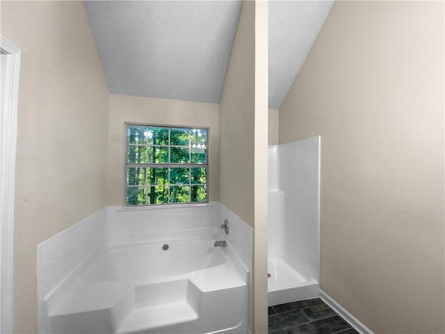 bathroom with lofted ceiling, a tub, and tile patterned floors