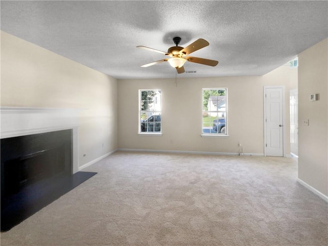 unfurnished living room with ceiling fan, a textured ceiling, and light colored carpet